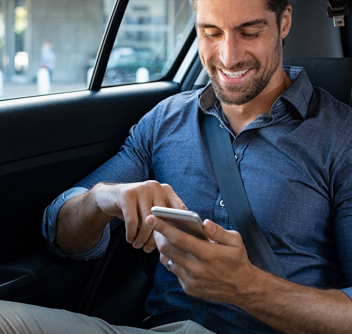 Man using a mobile phone in the back seat of a car.